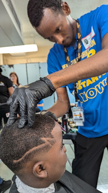 A student gives a hair cut to child.