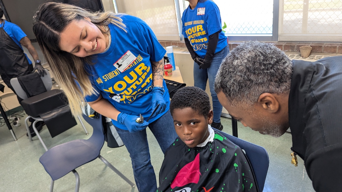 A student gives a hair cut to child.